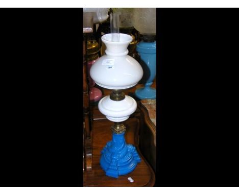 An oil lamp with 'dolphin' blue glass base, milk glass reservoir and shade
