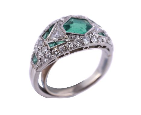 An Art Deco emerald and diamond dress ring, the tapering panel with a central octagonal cut emerald within a geometric surrou