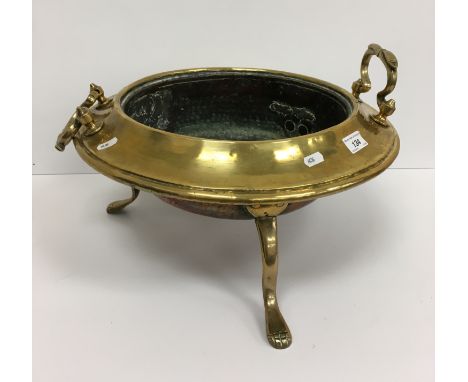 A brass and copper twin-handled dish / planter, raised on three legs to claw feet, 44 cm diameter excluding handles x 22 cm h