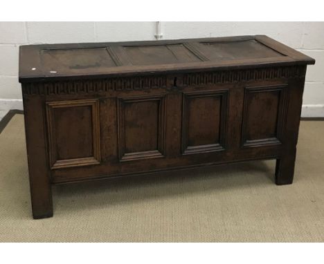 An 18th Century oak coffer, the three panel top with moulded edge above a carved frieze and plain four panel front on stile s