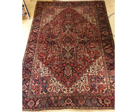 An early to mid 20th Century Indian carpet, the central panel set with stylised flower head medallion on a red with cream sty
