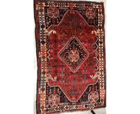 A Persian carpet, the central panel set with diamond shaped medallion on a red stylised floral decorated ground, within a ste