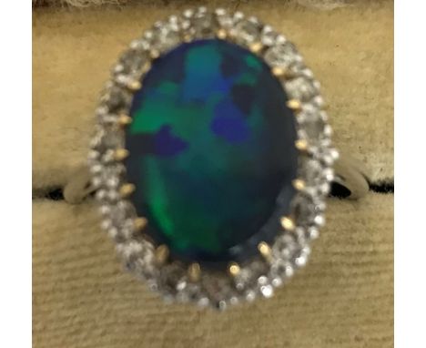 An 18 carat white gold cabochon opal and diamond set cluster ring, size O, 5.6 g CONDITION REPORTS Not UK hallmarked, just st