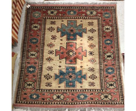 A Persian rug, the central panel set with three repeating medallions on a cream ground with stylised tarantula decoration wit