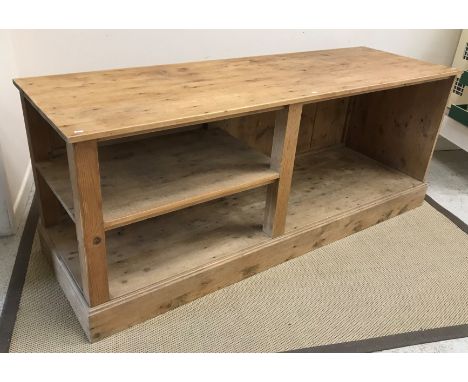 A 20th Century pine kitchen or shop unit, the plain top above an open recess and shelf, on a plinth base, 200 cm wide x 64.5 