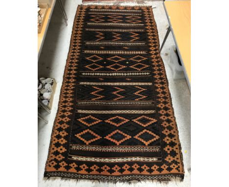 A Kelim rug, the central panel set with repeating lozenge medallion decorated panels on a brown ground within a brown and ter