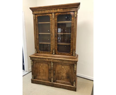 A Victorian walnut and marquetry inlaid bookcase cabinet, the moulded cornice over two glazed doors enclosing three shelves, 