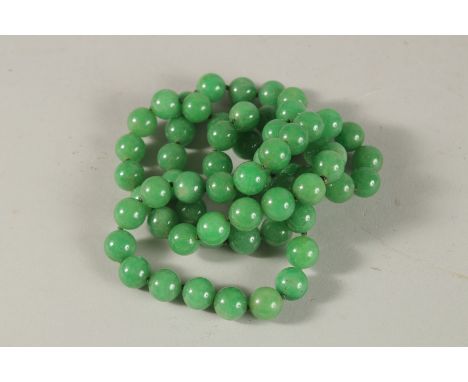 A LONG STRING OF JADE BEADS. 80cms long.