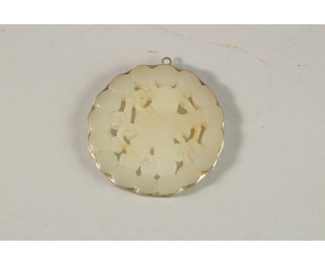 A CHINESE CARVED AND PIERCED CELADON JADE PENDANT. 5cms diameter.