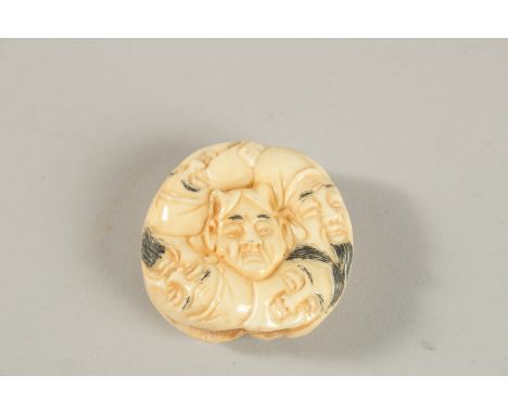 A CARVED BONE NINE-FACES NETSUKE.
