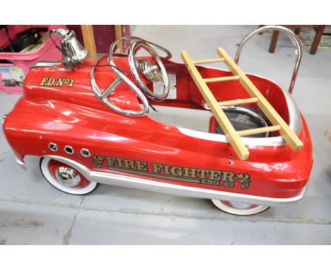 Contemporary children's pedal car in the form of a bright red fire engine complete with ladder