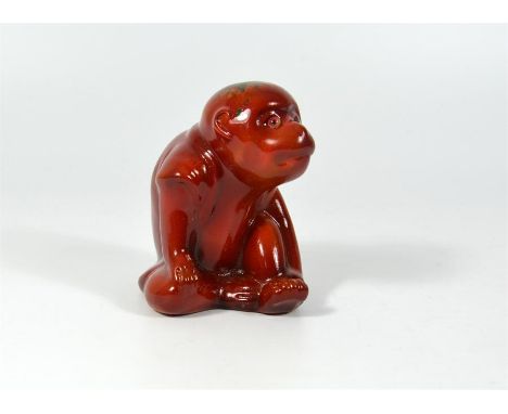 A Bernard Moore model of a seated monkey covered in a red lustre, flambe glaze. BM monogram inside base. Height 9.5cm.