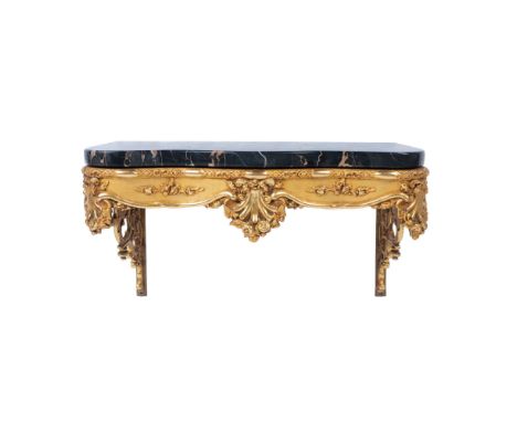 A heavily carved gilded wall mounted table with 1" thick dark Emperador marble shelf topper. Includes a pair of gilded cast m