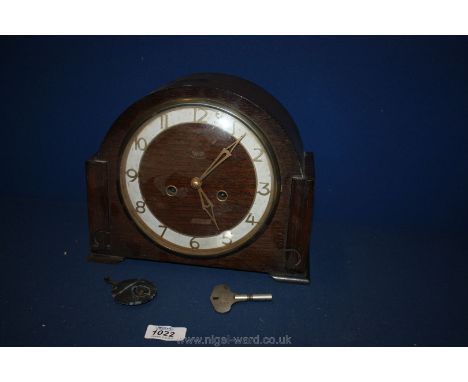 A wooden mantle Clock with pendulum and key.