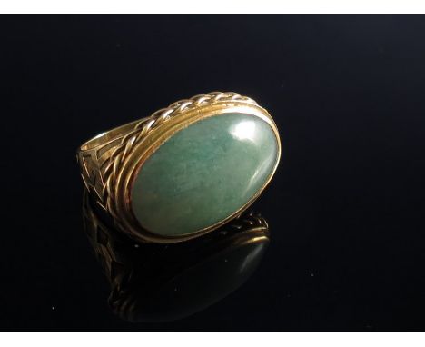 A large cabochon jade set ring in horizontal setting, patterned shoulders 