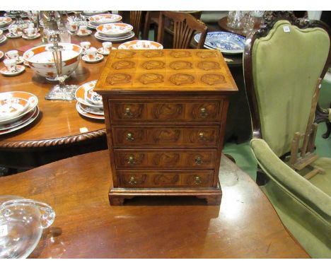 A miniature chest of drawers veneered in olive oysters on bracket feet