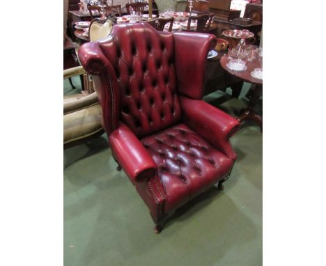A red leather wing back arm chair with deep button back and brass stud detail 