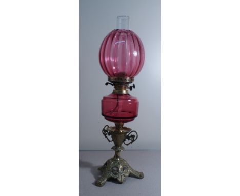 A late 19th/early century Duplex Cranberry glass oil lamp with melon fluted shade, plain reservoir over a brass ornate twin h