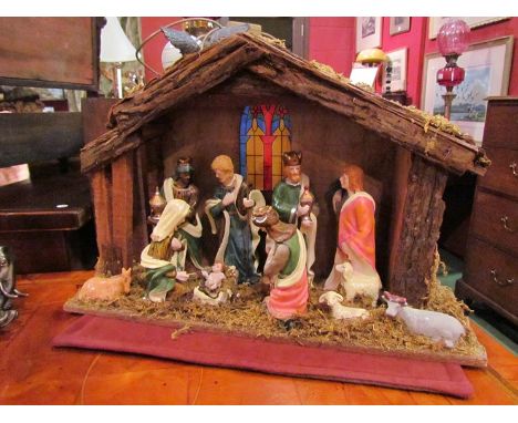 A wooden stable nativity scene with ceramic figures and illuminated stained glass effect window 
