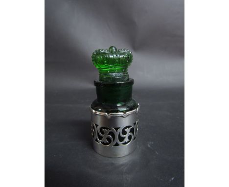 An Edwardian green glass scent bottle, with crown finial, by the Crown Perfume Company in a pierced decorative silver sleeve 