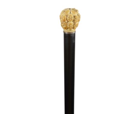An Edwardian novelty walking cane the Japanese ivory pommel carved with noh masks, silver collar, ebony shaft and bone ferrul