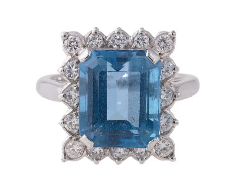 A blue topaz and diamond-set ringthe rectangular step cut-cornered blue topaz claw-set above the surround of brilliant-cut di