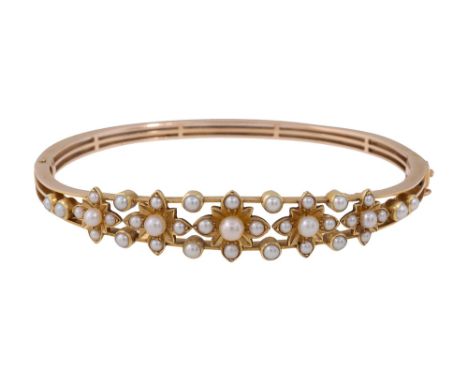 An Edwardian seed pearl hinge bangle an open-work central panel of pearls, set in a slightly graduating linear form of floral