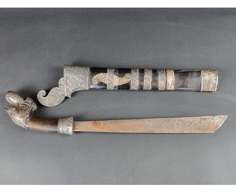 A 19th century Indonesian parang and scabbard, with 32.5cm blade, carved wood Dragon's head pommel and silver mounts to the h