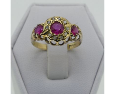 A three stone ruby Ring, the central circular facetted stone, 3.9mm diameter within a surround of single cut diamonds and wit