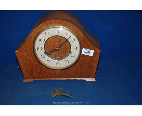 A wooden mantle Clock with beige face and gilt numbers, with key.