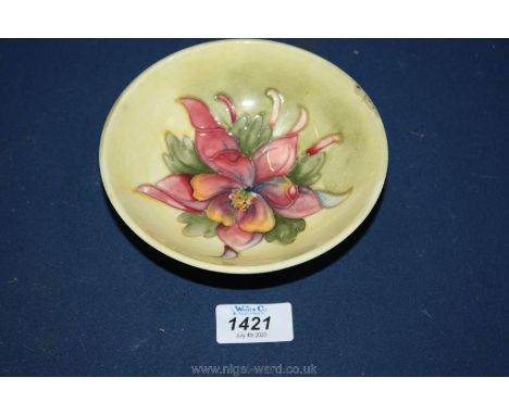 A Moorcroft dish with light green background, with lily centre, 5 1/2" diameter, some damage to rim.