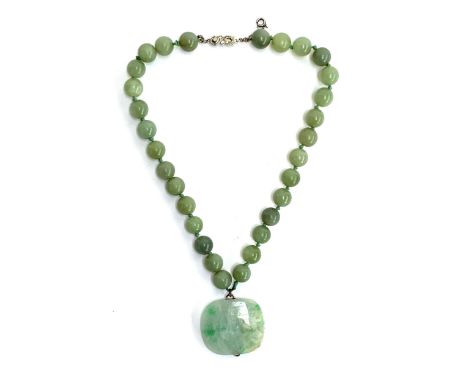 A jade bead necklace, the 30 beads each approx. 1.1cm, suspending a large jade pendant with yellow metal bales, 3.7cm wide; t
