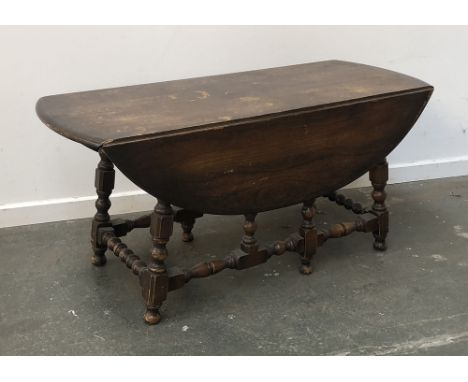 A mid-century Ercol elm drop-leaf coffee table on turned supports, 104cmL 