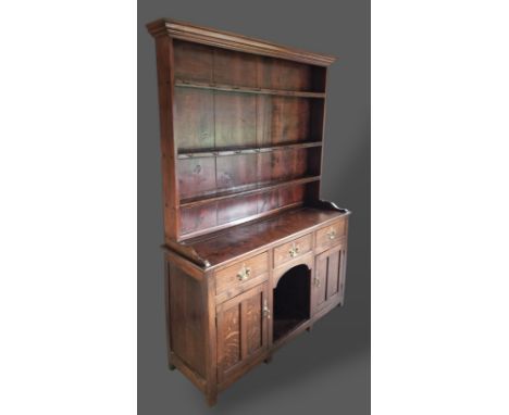 A George III oak dresser, the boarded shelf back above three drawers, two cupboard doors and central alcove flanked by stiles