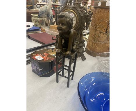 A BRONZE MODEL OF A CHILD KNEELING ON A STOOL SIGNED 