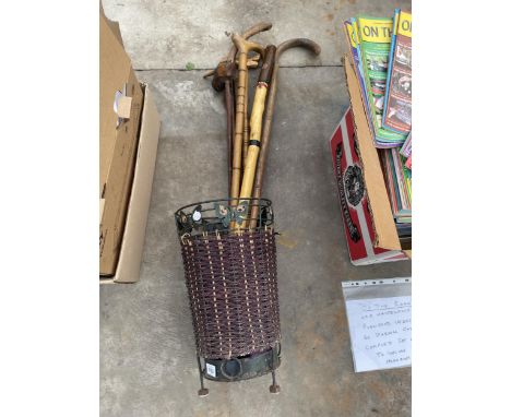 A WICKER STICK STAND WITH AN ASSORTMENT OF WALKING STICKS 