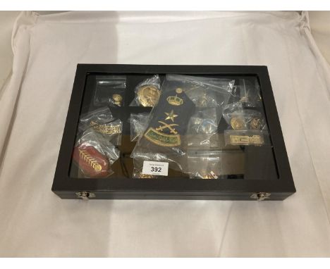 A DISPLAY CASE CONSTAINING TWENTY FIVE GULF MEDALS AND BADGES INCLUDING A PAIR OF SAUDI ARMY EPAULETTES, ETC 