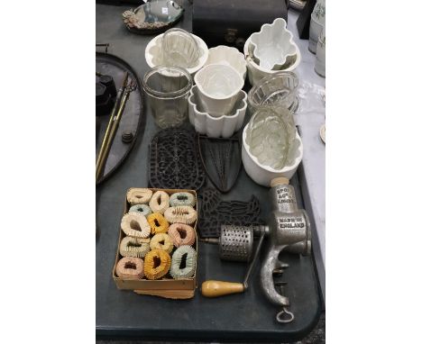 A MIXED LOT OF VINTAGE KITCHENALIA TO INCLUDE CERAMIC AND GLASS MOULDS, PIE DISH COLLARS, CAST TRIVETS AND A SPONG MINCER 