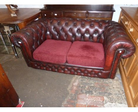 Red leather button upholstered Chesterfield type two seater sofa with fabric covered loose cushions