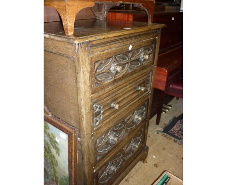 20th Century oak narrow chest of four long drawers with knob handles and carved decoration raised on bracket feet