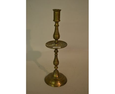 Antique brass candlestick with a cast drip tray raised on turned column support with domed circular base