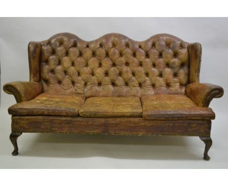 Early 20th Century brown buttoned leather upholstered wing back three seat sofa raised on low cabriole front supports