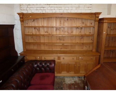 Large modern pine dresser with a boarded shelf back above four drawers and four panelled doors on bracket feet