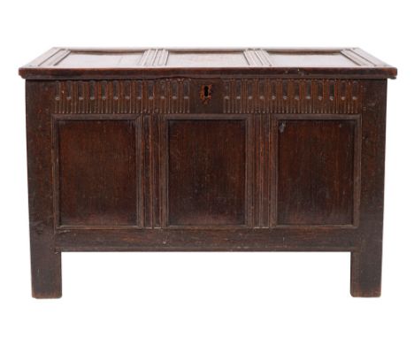 A 17th Century oak rectangular coffer of moulded panel construction with a hinged top, the front with a fluted frieze and tri