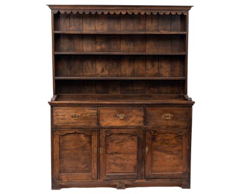 A  stained oak dresser in early 18th century style, 20th century; the plate rack with shaped canopy above three shelves, with