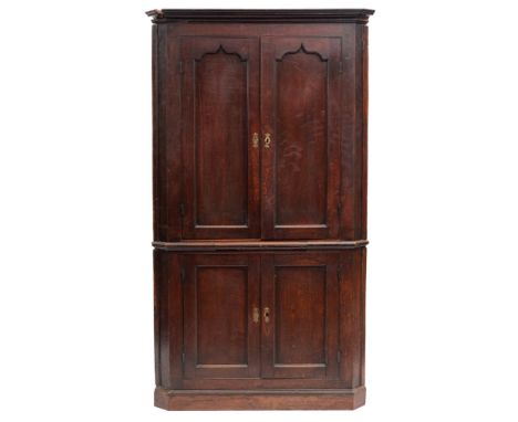 A George III oak corner cabinet, last quarter 18th century; with moulded cornice above two shallow Gothic arched panel doors,