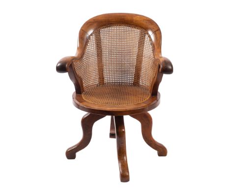 A Victorian walnut, birch and oak revolving office desk armchair with curved cane panel back, shaped arm supports and circula