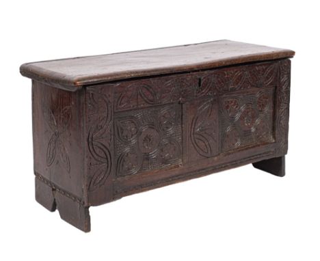 A Charles II oak coffer, circa 1670; the hinged cover above a two panel front, each carved in recessed relief with foliate ci