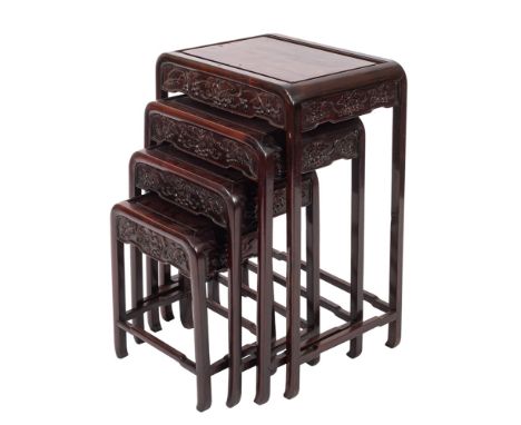 An early 20th century nest of Chinese hardwood tables, probably Zitan, of rounded rectangular form, the panel top with carved