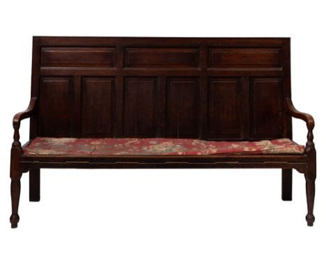 A George II or early George III oak settle, third quarter 18th century; with panel back and swept arms with downscrolled term